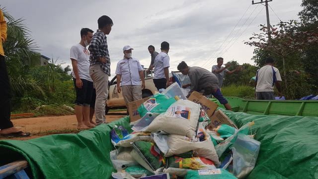 (Bertopi) Ketua Komisi A DPRD Kotawaringin Barat, Rizky Aditia Putra mendistribusikan bantuan sembako dan air mineral kepada warga yang terdampak banjir/InfoPBUN/foto: Lukman Hakim