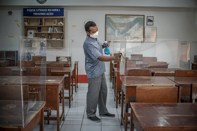 Penjaga sekolah membersihkan ruang kelas SMAN 81 Jakarta Timur jelang penambahan sekolah yang menggelar pembelajar tatap muka (PTM) pada Senin, (13/9). Foto: Iqbal Firdaus/kumparan