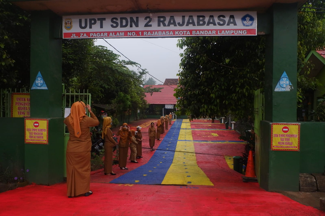 Para guru SDN 2 Rajabasa Bandar Lampung berbaris menyambut kedatangan siswa di hari pertama simulasi PTM terbatas, Senin (13/9) | Foto : Sidik Aryono/ Lampung Geh