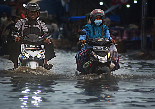 Pengendara sepeda motor melintasi genangan banjir di kawasan Pasar Induk Rau, Serang, Banten, Selasa (14/9/2021). Foto: Asep Fathulrahman/Antara Foto