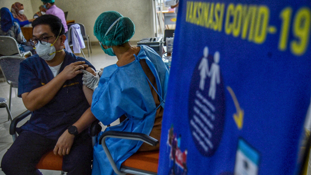 Petugas menyuntikkan vaksin Moderna kepada tenaga kesehatan yang menjalani vaksinasi COVID-19 dosis ketiga di Rumah Sakit Umum Pusat (RSUP) Haji Adam Malik, Medan, Sumatera Utara.  Foto: Fransisco Carolio/ANTARA FOTO