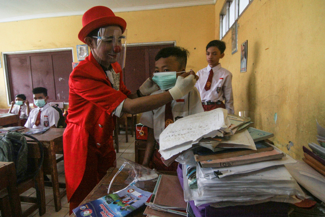 Seniman Aku Badut Indonesia (ABI) memasangkan masker kepada siswa di SDN 03 Citayam, Kabupaten Bogor, Jawa Barat, Senin (6/9/2021). Foto: Asprilla Dwi Adha/Antara Foto