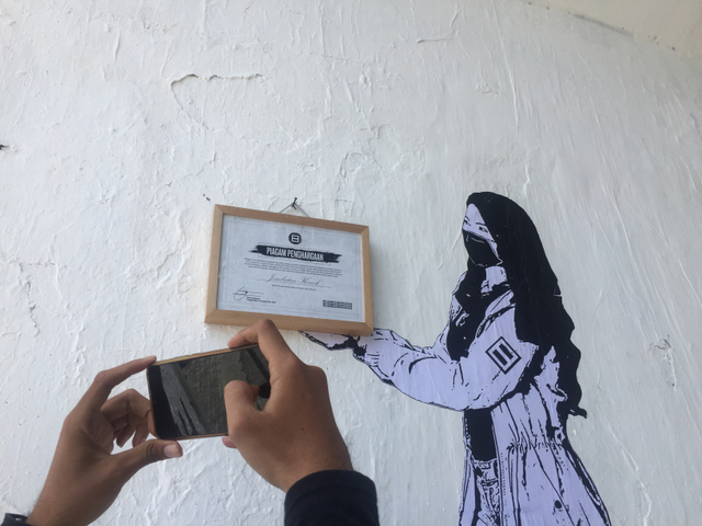Gejayan Memanggil pasang piagam di Jembatan Kewek, Yogyakarta. Mereka juga umumkan pemenang 'Lomba Mural Dibungkam' Foto: Arfiansyah Panji Purnandaru/kumparan