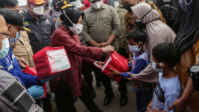 Menteri Sosial Tri Rismaharini (kiri) menyerahkan bantuan sosial kepada warga saat kunjungan kerja di dapur umum korban banjir di Jalan Anoi, Palangkaraya, Kalimantan Tengah, Kamis(15/9/2021). Foto: Makna Zaezar/ANTARA FOTO