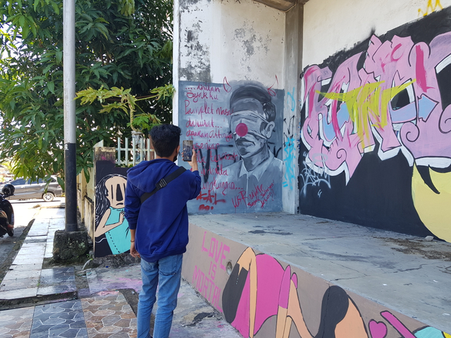 Warga mengabadikan Mural mirip Presiden jokowi. (Anjar)