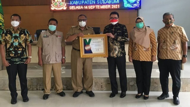 BPJS Kesehatan menyerahkan piagam penghargaan kepada Pemkab Sukabumi atas pencapaian UHC dalam kepesertaan Program JKN-KIS, di Pendopo Kabupaten Sukabumi. Foto: Dok. BPJS Kesehatan