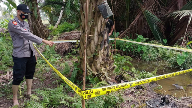 Polisi menunjukkan lokasi penemuan Zulkifli dalam kondisi tak bernyawa dan hangus terbakar di areal kebun sawit Dusun Muda Kari, Gampong, Matang Pupanji. Foto: Dok. Istimewa