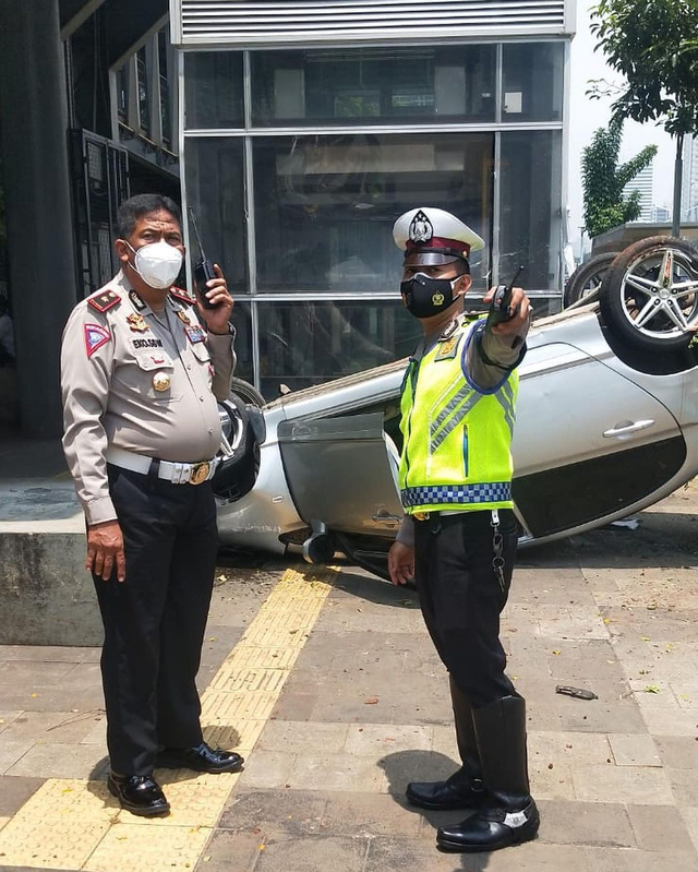 Polisi di lokasi kendaraan yang terbalik di depan Polda Metro Jaya, Jl. Jend. Sudirman, Jakarta Selatan. Foto: Instagram/@tmcpoldametro