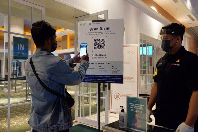 Seorang pengunjung melakukan scan QR Code lewat aplikasi PeduliLindungi sebelum masuk ke bioskop XXI di Sleman City Hall. Foto: istimewa
