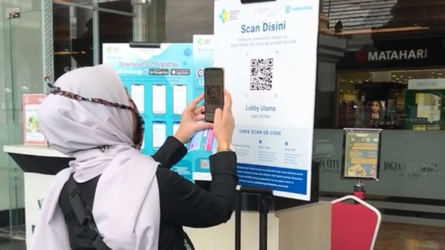 Seorang pengunjung sedang melakukan scan QR code dengan aplikasi PeduliLindungi di Jogja City Mall. Foto: dok. JCM