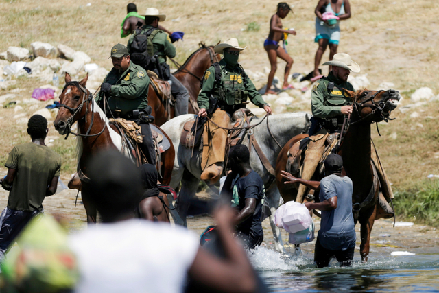 Petugas penegak hukum AS yang menunggang kuda memblokir jalan bagi para migran yang mencapai pantai Rio Grande di Texas, AS, Minggu (19/9). Foto: DANIEL BECERRIL/REUTERS
