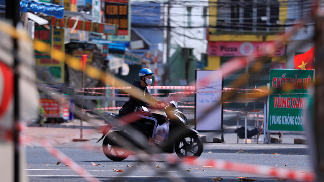 Seorang pria mengendarai skuter melewati barikade jalan yang terbuat dari perancah dan pita pembatas di Vung Tau, Vietnam, Senin (20/9). Foto: Hau Dinh/AP Photo