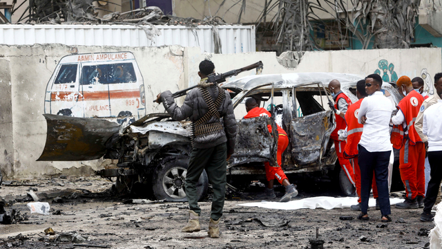 Seorang petugas polisi berjaga-jaga saat pekerja mengeluarkan jenazah korban di lokasi ledakan bom mobil bunuh diri di dekat kediaman presiden, di Mogadishu, Somalia, Sabtu (26/9). Foto: Feisal Omar/REUTERS