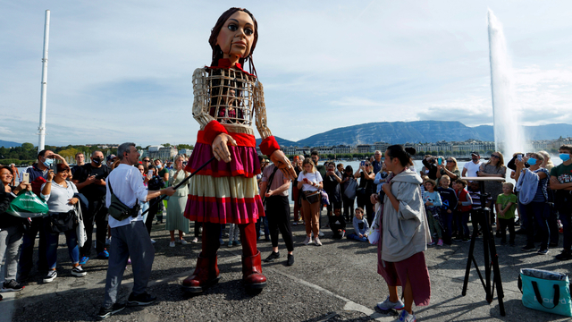 Orang-orang melihat Little Amal, boneka setinggi 3,5 meter yang menggambarkan pengungsi Suriah, di Bains des Paquis di Jenewa, Swiss, Selasa (28/9). Foto: Denis Balibouse/REUTERS