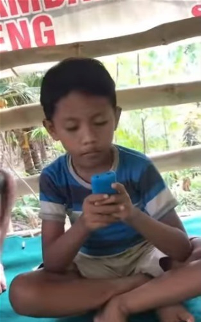 Momen sedih seorang bocah melihat temannya pakai gadget main gim online saat dirinya hanya memiliki HP jadul. (Foto: Instagram/@dagelan)