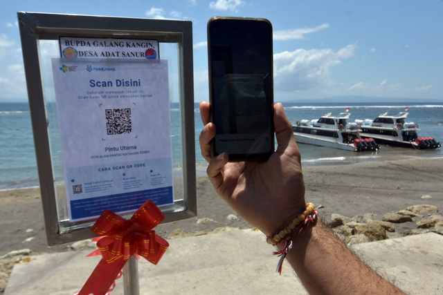 Pengunjung memindai kode batang sertifikat vaksin COVID-19 menggunakan aplikasi PeduliLindungi saat berkunjung di Pantai Sanur, Denpasar, Bali, Kamis (30/9/2021). Foto: Nyoman Hendra Wibowo/Antara Foto