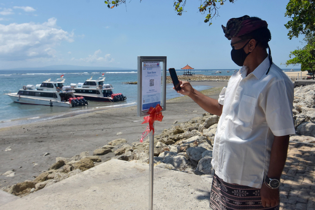 Warga memindai kode batang sertifikat vaksin COVID-19 menggunakan aplikasi PeduliLindungi saat berkunjung di Pantai Sanur, Denpasar, Bali, Kamis (30/9/2021). Foto: Nyoman Hendra Wibowo/Antara Foto