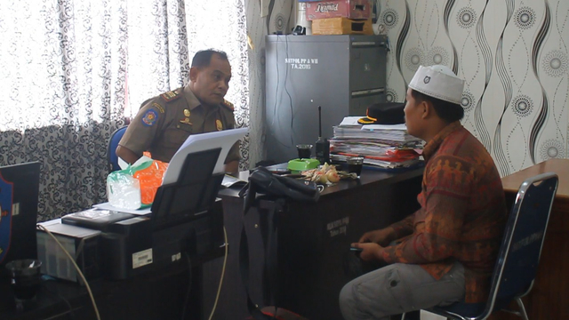 Petugas Satpol PP Kabupaten Aceh Barat meminta keterangan dari pria yang diamankan saat menggalang dana membawa proposal yang mengatasnamakan Yayasan Mualaf Center dengan dugaan memalsukan tanda tangan, Selasa (5/10). Foto: Siti Aisyah/acehkini