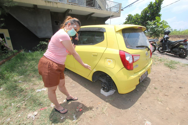 Lili Pratiwi menunjukkan ban mobilnya yang raib digondol maling. foto/Ulul Azmy