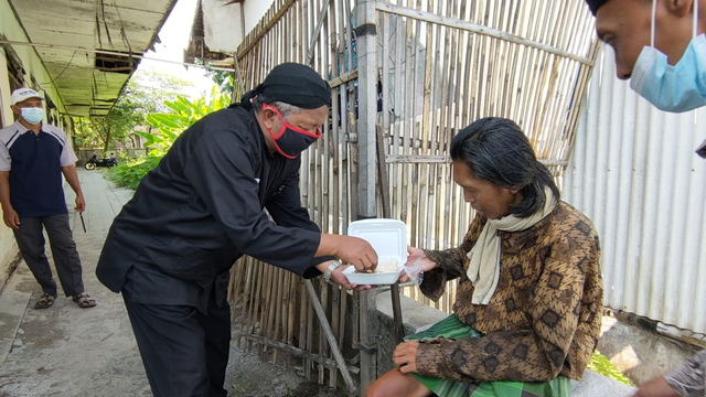 Kepala Desa (Kades) Sidowayah, Klaten, Mujahid Jaryanto memberikan nasi kotak kepada warga yang sakit. FOTO: Agung Santoso