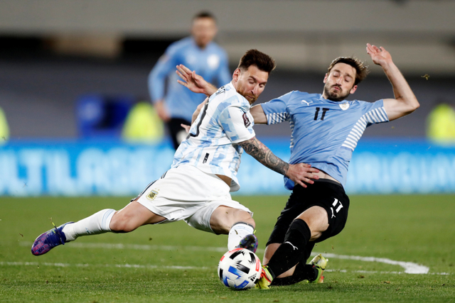 Pemain timnas Argentina Lionel Messi berebut bola dengan pemain timnas Uruguay Matias Vina pada pertandingan Kualifikasi Piala Dunia 2022 zona Amerika Selatan di stadion El Monumental, Buenos Aires, Argentina. Foto: Agustin Marcarian/REUTERS