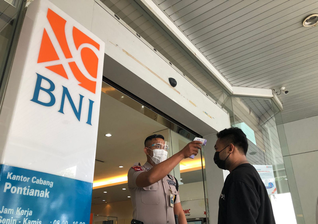 Petugas keamanan melakukan pemeriksaan suhu kepada nasabah yang masuk ke kantor BNI Cabang Pontianak. BNI mewajibkan nasabahnya telah melakukan vaksinasi corona dan memiliki aplikasi Peduli Lindungi, jika hendak mendapatkan pelayanan perbankan. Foto: Leo Prima/Hi!Pontianak 