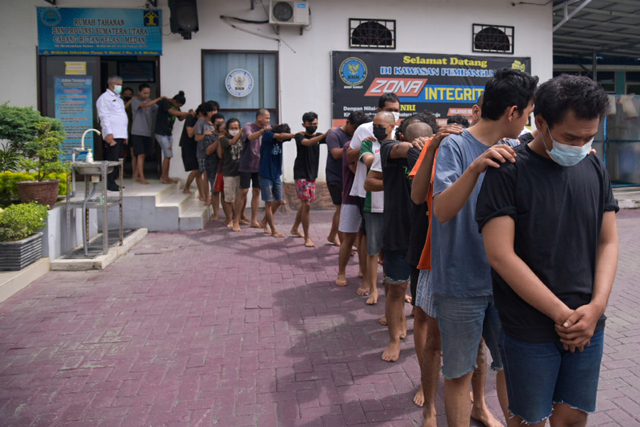 Petugas menggiring mahasiswa yang diamankan saat ungkap kasus di Kantor Badan Narkotika Nasional (BNNP) Provinsi Sumatera Utara, Percut Sei Tuan, Deliserdang, Sumatera Utara, Senin (11/10/2021). Foto: Fransisco Carolio/Antara Foto