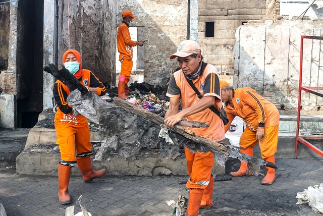 Petugas PPSU Cipinang Utara dan Sudin Sumber Daya Air Jakarta Timur membersihkan puing-puing dan reruntuhan dari sejumlah bangunan yang terbakar di kawasan Pasar Gembrong, Jakarta Timur, Selasa (11/5). Foto: Iqbal Firdaus/kumparan