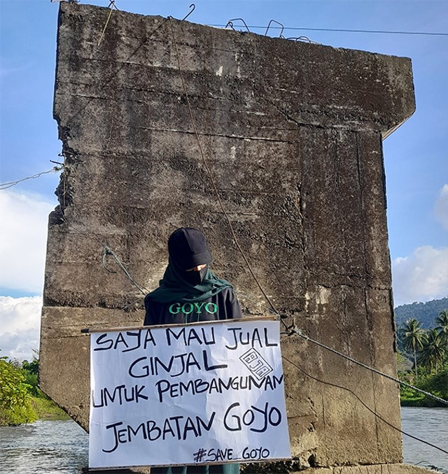 Alin Pangalima, perempuan asal Desa Olot II, Kecamatan Bolangitang Barat, Kabupaten Bolmong Utara (Bolmut), memegang spanduk tentang keinginannya menjual ginjal untuk pembangunan jembatan Goyo. (foto: facebook Alin Pangalima)
