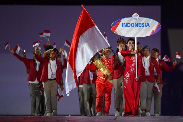 Anggota kontingen Indonesia mengibarkan bendera nasional mereka saat upacara pembukaan SEA Games ke-31 di Stadion Nasional My Dinh di Hanoi, Vietnam, Kamis (12/5/2022). Foto: Nhac NGUYEN/AFP