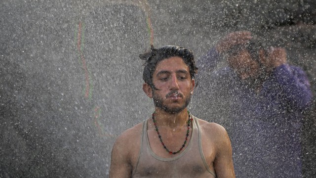 Seorang pria mandi pada hari musim panas di Islamabad, Pakistan pada 30 April 2022. Foto: Farooq Naeem/AFP