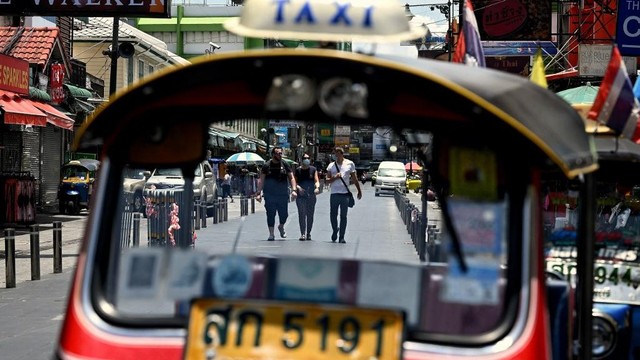 Turis asing terlihat melalui kaca depan tuk-tuk di sepanjang Jalan Khaosan, Bangkok, Thailand pada Selasa (17/5/2022). Foto: Lillian Suwanrumpha/AFP