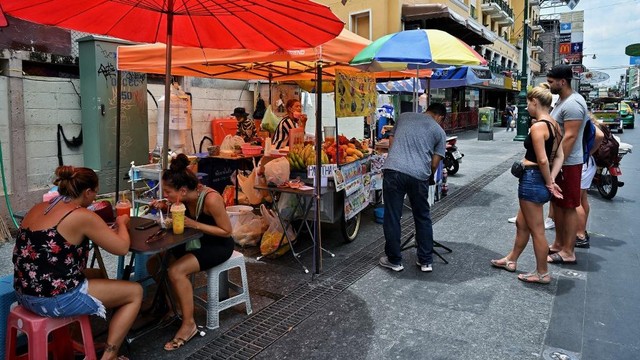 Turis menyantap makanan di sepanjang Jalan Khaosan, Bangkok, Thailand pada Selasa (17/5/2022). Foto: Lillian Suwanrumpha/AFP