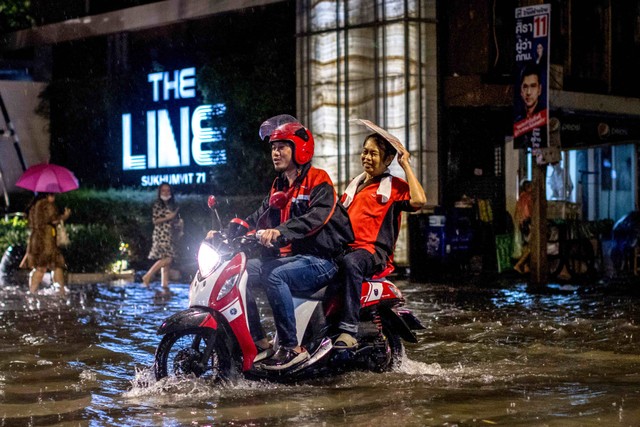 Ilustrasi pemotor yang melewati banjir. Foto: Jack Taylor/AFP