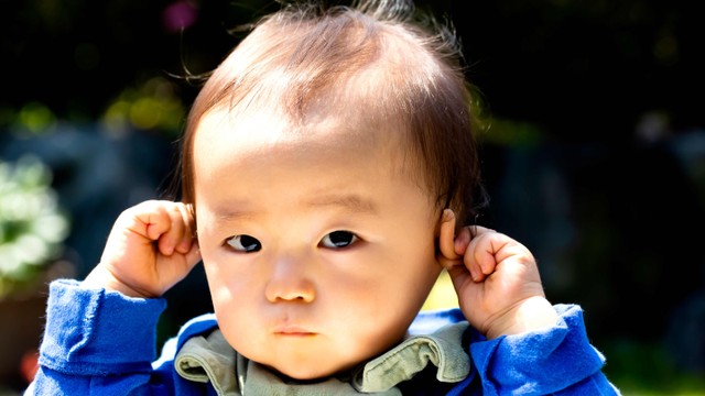 Bayi memegang telinga. Foto: minianne/Shutterstock