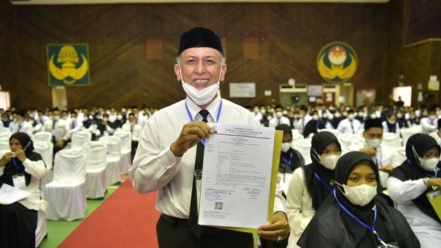 Tarmizi menerima SK pengakatan Pegawai Pemerintah dengan Perjanjian Kerja (PPPK) Pemerintah Aceh di GOR Arun, Lhokseumawe, Kamis (19/5/2022), setelah mengabdi sebagai guru honorer selama 33 tahun 3 bulan. Foto: Dok. Disdik Aceh
