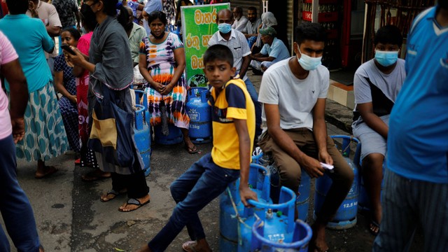 Warga menduduki tabung gas sembari menunggu antrean untuk membeli gas ke agen pusat distribusi saat krisis ekonomi di Kolombo, Sri Lanka, Jumat (20/5/2022). Foto: Adnan Abidi/REUTERS