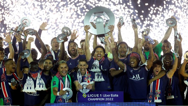 Pemain Paris St Germain Marquinhos mengangkat trofi dan merayakan dengan anggota tim setelah memenangkan Ligue 1, di Parc des Princes, Paris, Prancis, Sabtu (21/5/2022). Foto: Christian Hartmann/REUTERS