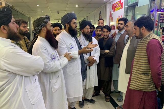Maulvi Fatih dan para pejabatnya berbincang dengan para penjaga toko dan warga yang berkumpul di sebuah mal di Kabul.