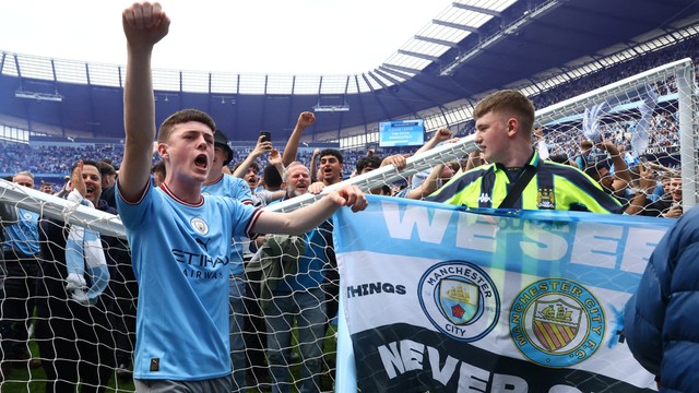 Penggemar merayakan di lapangan setelah Manchester City memenangkan Liga Premier di Stadion Etihad, Manchester, Inggris, Minggu (22/5/2022). Foto: Hannah McKay/REUTERS