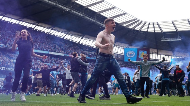 Penggemar merayakan di lapangan setelah Manchester City memenangkan Liga Premier di Stadion Etihad, Manchester, Inggris, Minggu (22/5/2022). Foto: Hannah McKay/REUTERS
