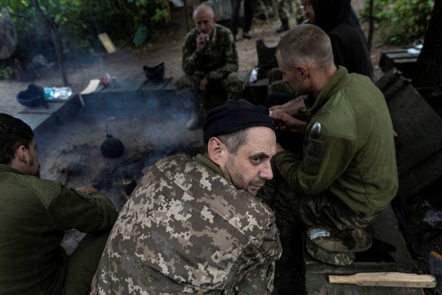 Anggota angkatan bersenjata Ukraina beristirahat sembari memasak makanan di dekat Donetsk, Ukraina, Minggu (22/5/2022). Foto: Carlos Barria/REUTERS