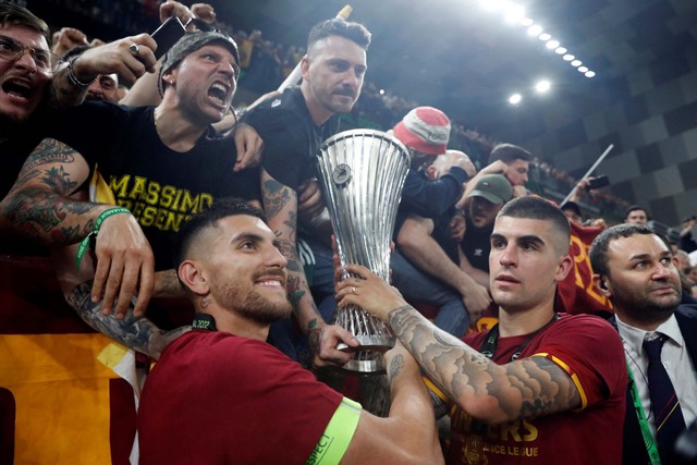 Pemain AS Roma, Lorenzo Pellegrini dan Gianluca Mancini merayakan dengan fans saat mengangkat trofi setelah memenangkan Liga Konferensi Eropa. Foto: Bernadett Szabo/REUTERS