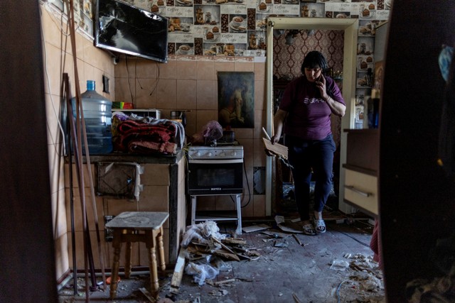 Seorang wanita membersihkan bagian-bagian rumahnya yang hancur setelah serangan rudal di stasiun kereta api, di Pokrovsk, wilayah Donetsk, Ukraina, Rabu (25/5/2022). Foto: Carlos Barria/REUTERS
