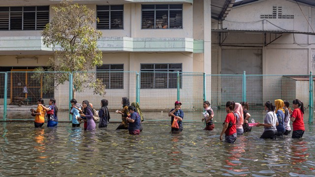Sejumlah karyawan kawasan industri pelabuhan berjalan menerobos banjir limpasan air laut ke daratan atau rob seusai membersihkan pabrik mereka di kawasan industri Pelabuhan Tanjung Emas Semarang, Jawa Tengah, Jumat (27/5/2022). Foto: Aji Styawan/ANTARA FOTO