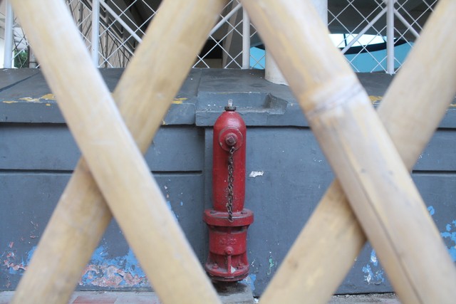 Ilustrasi dalam satu jepretan foto sebuah hydrant terperangkap dalam dua pilar X dari bambu, sama halnya dengan seseorang (hydrant bewarna merah) yang terperangkap antara dua rasa senang & sedih (dua pilar X) dalam satu hari. Foto : Andini Putri Nurazizah