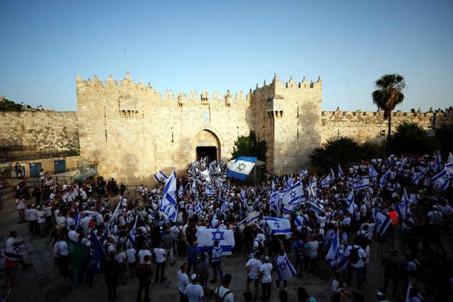 Warga Israel menari dan bernyanyi sambil memegang bendera nasional Israel di dekat Gerbang Damaskus ke Kota Tua Yerusalem. Foto: Ammar Awad/REUTERS