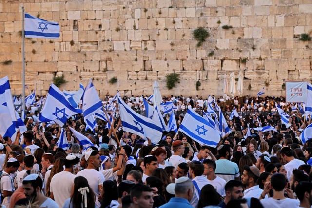 Ratusan orang mengibarkan bendera Israel dalam acara pawai bendera memperingati Hari Yerusalem di alun-alun di luar Kota Tua Yerusalem, Minggu (29/5/2022). Foto: Gil Cohen-MAGEN/AFP