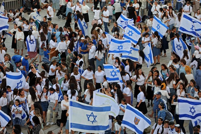 Ratusan orang mengibarkan bendera Israel dalam acara pawai bendera memperingati Hari Yerusalem di alun-alun di luar Kota Tua Yerusalem, Minggu (29/5/2022). Foto: Gil Cohen-MAGEN/AFP