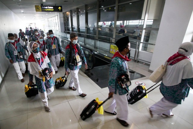 Jamaah calon haji kelompok terbang (kloter) pertama embarkasi Surabaya berjalan menuju pesawat di Terminal 2 Bandara Internasional Juanda Surabaya di Sidoarjo, Jawa Timur, Sabtu (4/6/2022).  Foto: Umarul Faruq/ANTARA FOTO